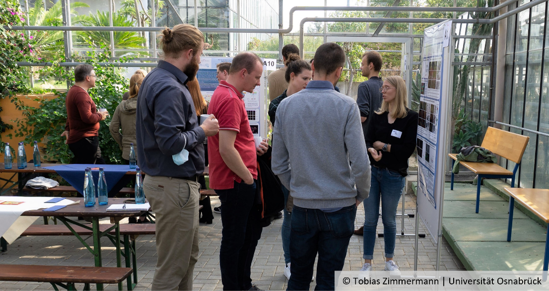 Teilnehmende des SFB-Symposiums diskutieren an einem Poster, © Tobias Zimmermann | Universität Osnabrück