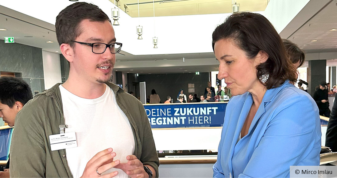 A man and a woman in conversation at an exhibition stand.